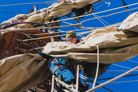 Sailors work with sails at a height on a traditional sailboatの写真素材