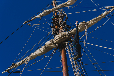 Sailors work with sails at a height on a traditional sailboatの写真素材