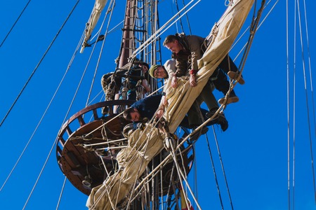 Sailors work with sails at a height on a traditional sailboatの写真素材