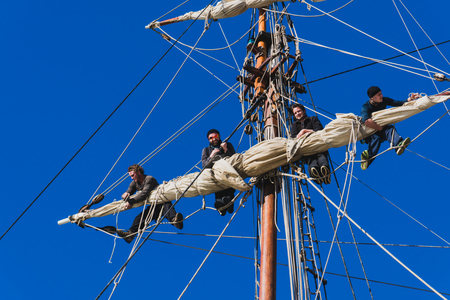 Sailors work with sails at a height on a traditional sailboatの写真素材