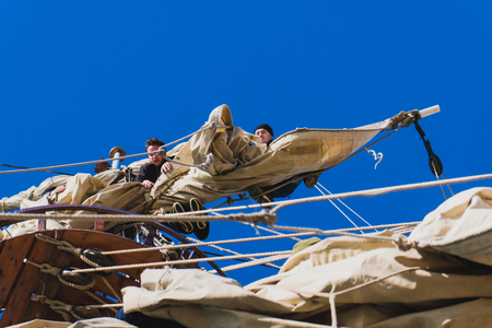 Sailors work with sails at a height on a traditional sailboatの写真素材
