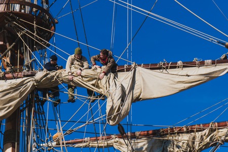 Sailors work with sails at a height on a traditional sailboatの写真素材