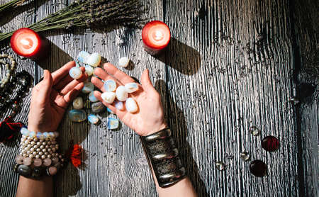 Fortuneteller's hands with stone runes, top view. Prediction of the future. Mystic interior. Occult symbols, rosaries, candles, dry lavenderの写真素材