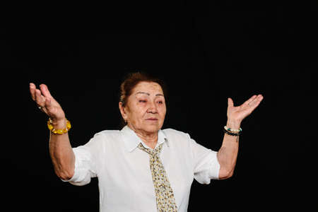 Portrait of an elderly senior Asian woman, raising her hands in a question gesture, like saying;...