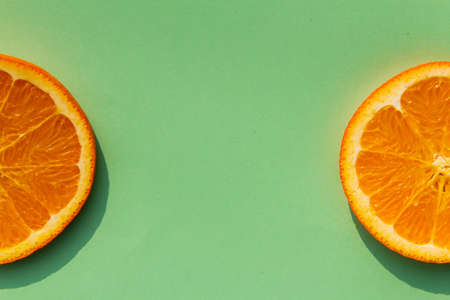 Bright, tasty, fresh, juicy orange slices on green background, natural vegan food, good for alphabet, vitamins for immune systemの写真素材
