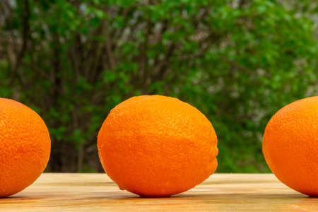 Close up of a fresh bright tasty orange on a wooden table in the garden, natural vegan foodの写真素材