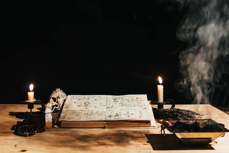 Occult white magic ritual of fire using grimoire, old book, candles