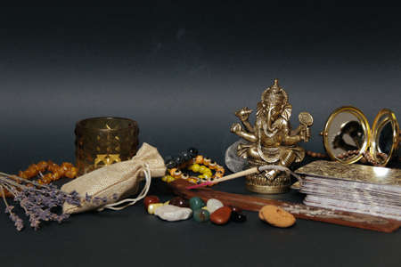 Table with occult attributes, top view. Ganesha figurine, stone rosaries, candles, aroma stick