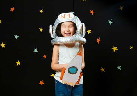 Portrait of a cute little Aisan girl, space at home, dreaming and playing astronaut. Funny family momentsの写真素材