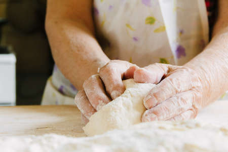 Cooking at home, old woman's hands kneading doughの写真素材