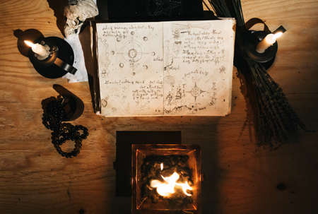 Occult white magic ritual of fire using grimoire, old book, candlesの写真素材