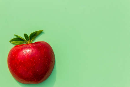 Fresh tasty red apple on green background, good for vegan food, alphabet and your advertisement, vitamins for immune systemの写真素材