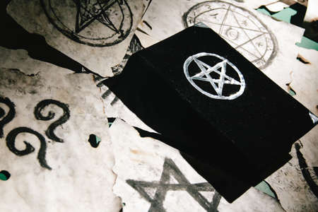 Occult grimoire, black magic book laying on table with occult symbols, candles, pentagrams, fortune telling, ritual, altar, spiritism, secret knowledge, scullの写真素材