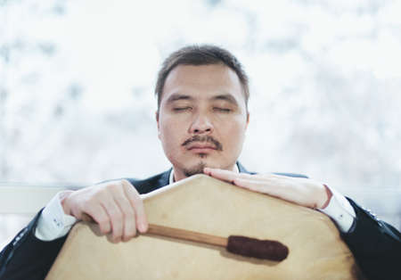 Asian businessman with shamanic tambourine. Concept of attracting success, wishing good luck to business. Money increasing.の写真素材