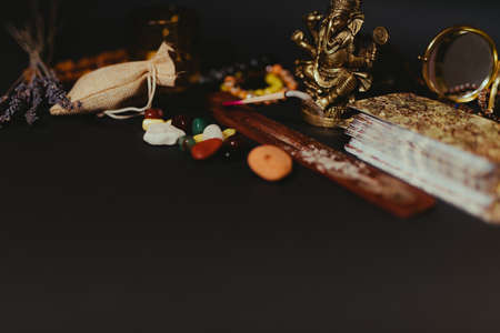 Occult altar with figurine of god Ganesha, candles, aroma stick, stones, dry herbs. Black background. Empty copy spaceの写真素材