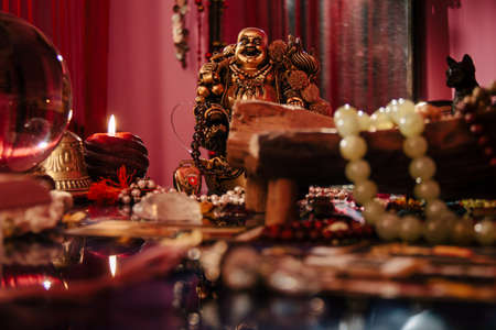 Occult interior, table with mystical symbols. Candles, Buddha figurine, crystal orb, stone rosary.の写真素材