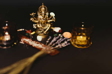Occult symbols laid out on a black background. Aroma stick, Buddha figurine, Ganesha figurine, stone...
