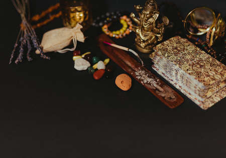 Occult symbols laid out on a black background. Aroma stick, Buddha figurine, Ganesha figurine, stone...