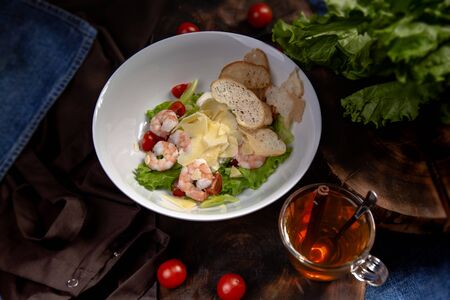 Caesar salad with shrimp and crackers in a plate on apron backgroundの写真素材