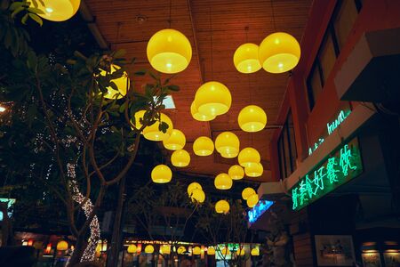 Yellow lanterns on the ceiling in front of a hotel in Thailand at nightの写真素材