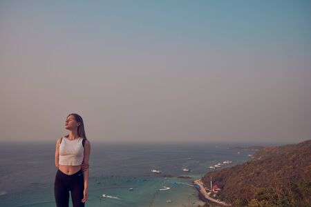Girl model against the sea and ocean in peas and on stones in shorts and swimsuit in Thailandの写真素材