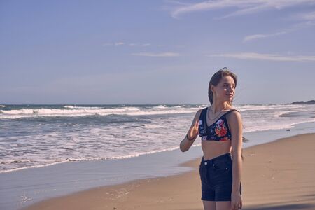 Girl model against the sea and ocean in peas and on stones in shorts and swimsuit in Thailandの写真素材