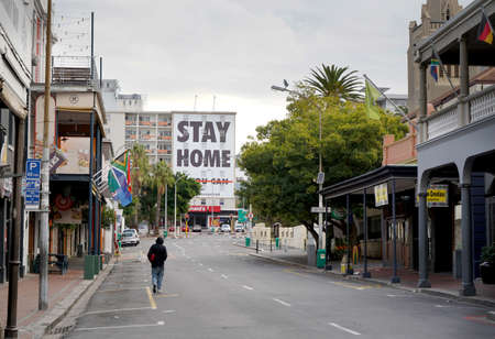 Cape Town, South Africa - 6 April 2020 : Empty streets with lonely figure and stay home sign in Cape...