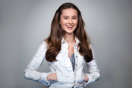 Close up shot of stylish young woman in smiling in front of grey background.の写真素材