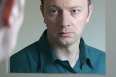 Man takes a look at himself in the mirror.の写真素材