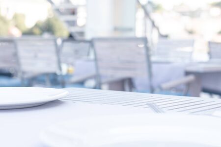 White plate on blurred bakground. Wooden table in restraunt. Blurred backgroundの写真素材