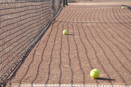 Tennis balls on the playing field near the grid.の写真素材