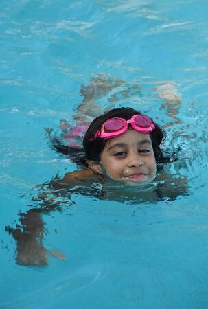 girl swimming wearing pink gogglesの写真素材