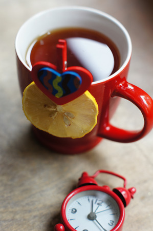 wooden table for breakfast with cup of tea with lemon and watchの写真素材