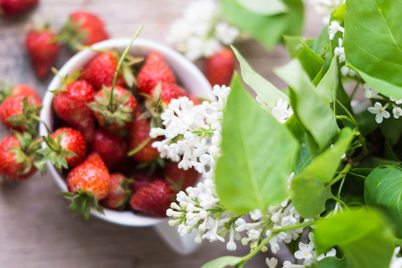 Fresh strawberries and white lilac flowers on the old wooden tableの写真素材