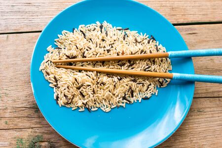wild rice in ceramic bowl and chopsticks on wooden backgroundの写真素材