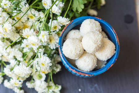 candy in coconut chips on a wooden tableの写真素材