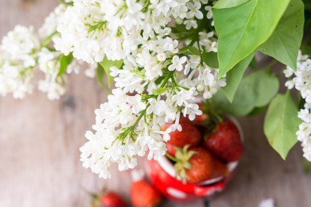 Fresh strawberries and white lilac flowers on the old wooden tableの写真素材
