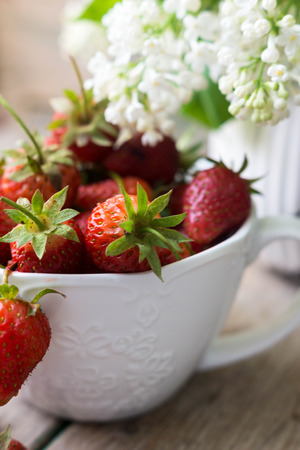 Fresh strawberries and white lilac flowers on the old wooden tableの写真素材
