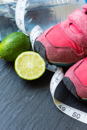 Sport shoes,  lime,tennis ball  and water on black backgroundの写真素材