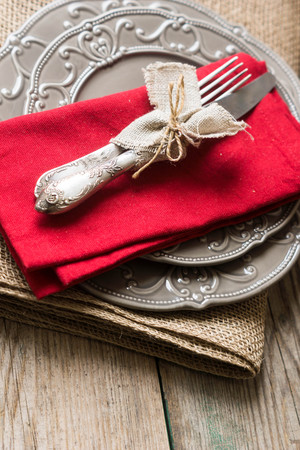 Table setting: plates, vintage fork, knife and spoon with napkin on rustic wooden table. Top view point.の写真素材