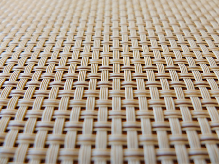 close-up of a beige fabric plastic lattice, grid texture; pattern of horizontal and vertical interwoven lines may be used as a background; photo taken in perspective with focus in the centerの写真素材