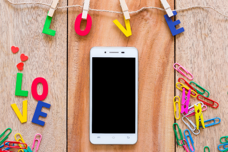 Smartphone with Valentine's day love Letter on wooden board background with copy space.の写真素材