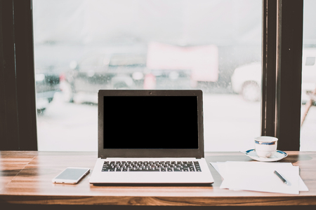 Mockup image of laptop with blank black screen on wooden table of In the coffee shop.の写真素材