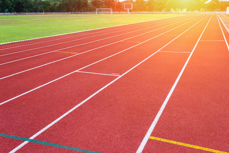 White lines of stadium and texture of running racetrack red rubber racetracks in outdoor stadium are 8 track and green grass fieldの写真素材