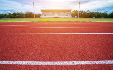 White lines of stadium and texture of running racetrack red rubber racetracks in outdoor stadium are 8 track and green grass fieldの写真素材