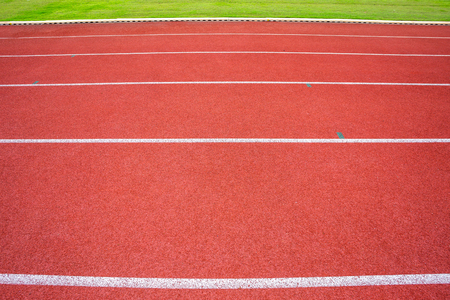 White lines of stadium and texture of running racetrack red rubber racetracks in outdoor stadium are 8 track and green grass fieldの写真素材
