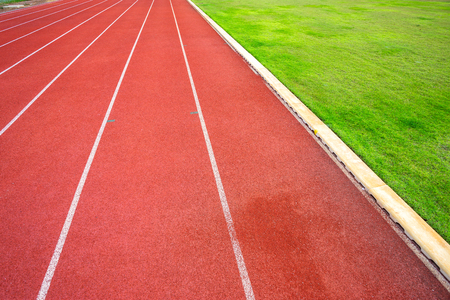 White lines of stadium and texture of running racetrack red rubber racetracks in outdoor stadium are 8 track and green grass fieldの写真素材