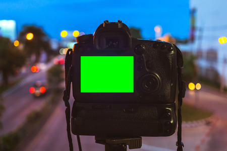 Close-up of DSLR Camera capturing on colorful light abstract circular bokeh background,Night time,Mockup image of with blank screen,DSLR on Tripod,Green screen.の写真素材