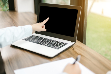 Close-up of business female working pointing at her laptop and make a note in coffee shop like the background.の写真素材