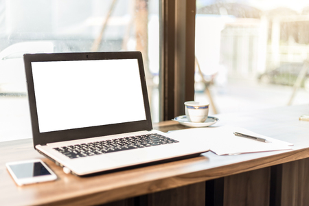 Mockup image of laptop with blank white screen,smartphone,coffee cup on wooden table of In the coffee shop.の写真素材